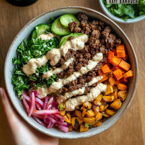 "Un bol de burger sain avec des légumes colorés, bœuf haché, avocat et sauce crémeuse."